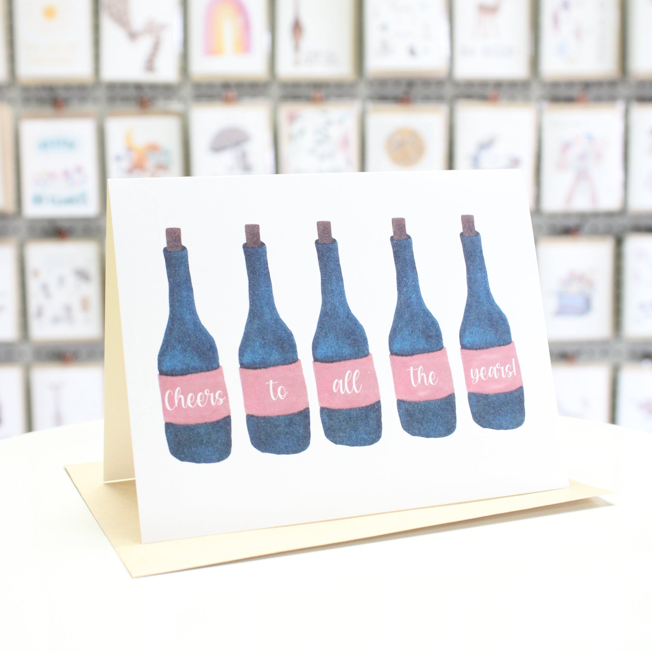 Hand crafted greeting card with watercolor wine bottles reading "cheers to all the years"