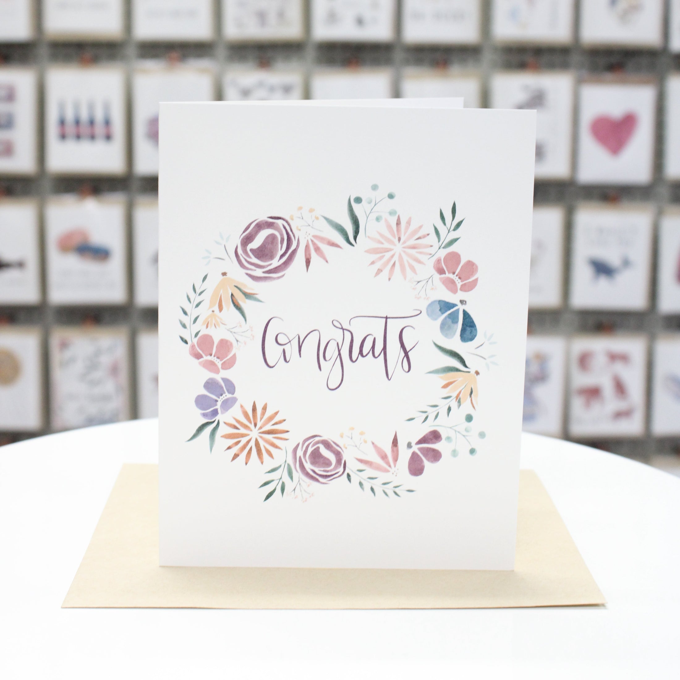 Hand crafted greeting card with watercolor spring flowers circling Congrats.