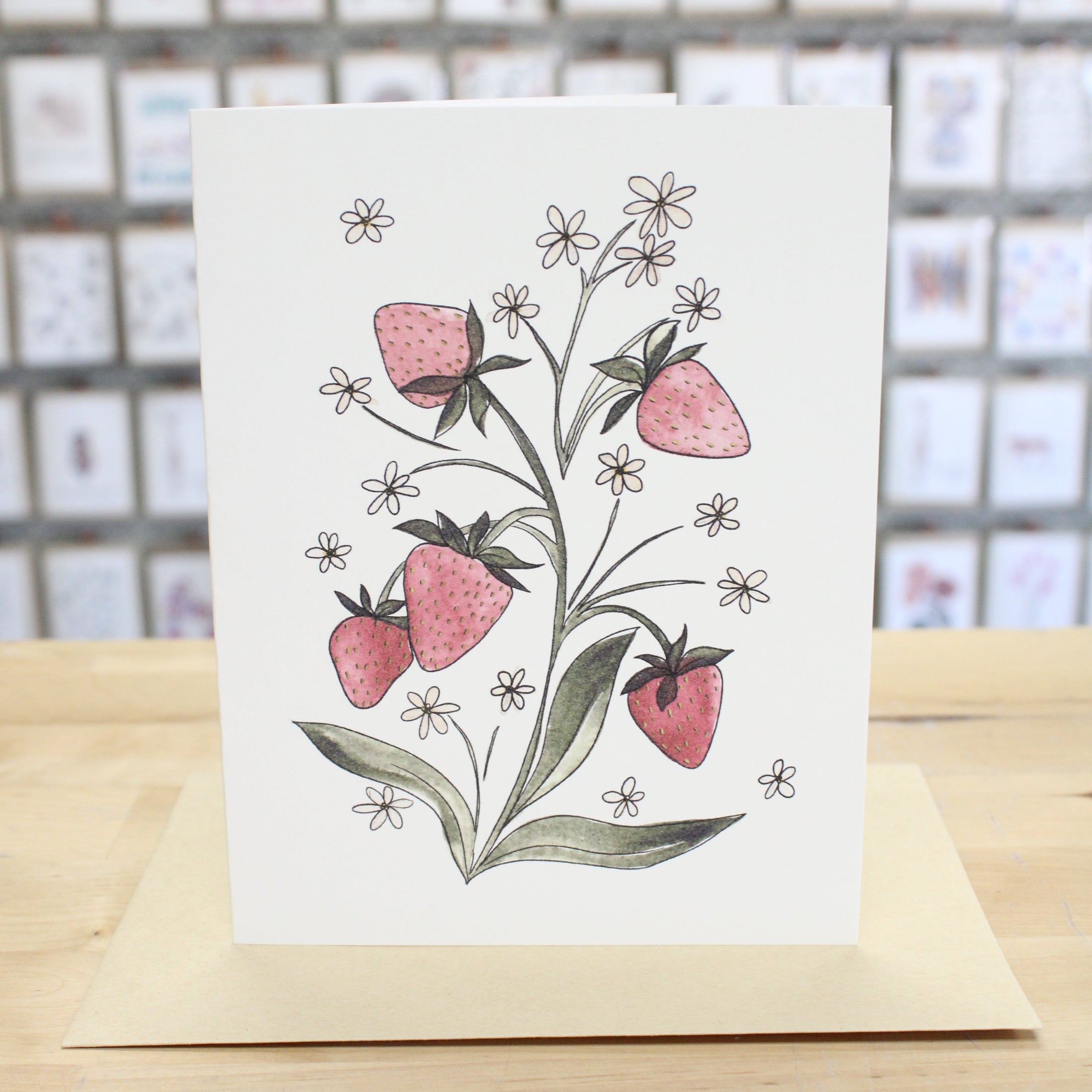 Hand crafted greeting card with hand drawn and water colored growing strawberries and white flowers. 