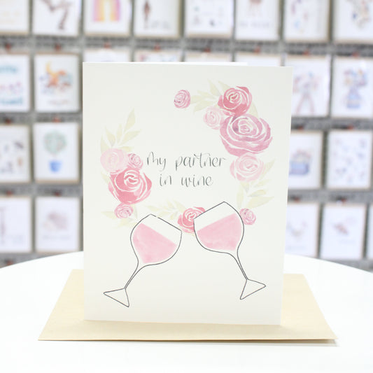 Hand crafted greeting card with water color flower wreath and wine glasses. The words "My Partner In Wine" inside the flower wreath. 
