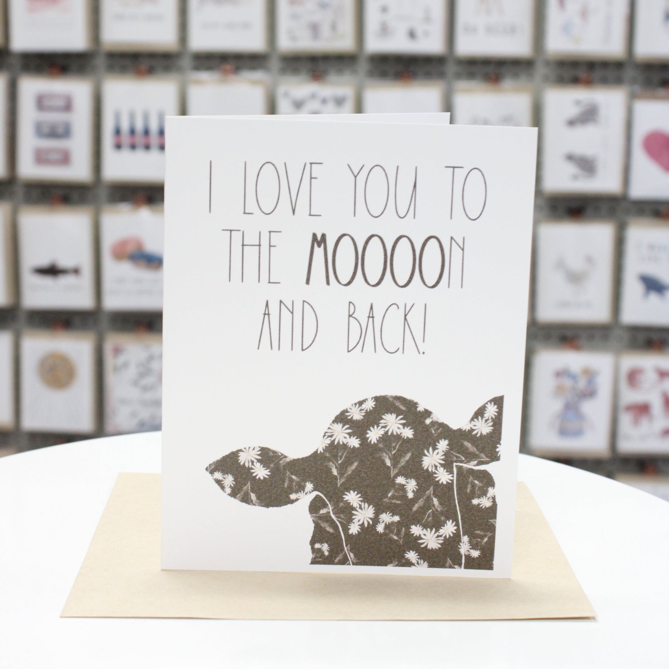 Hand crafted greeting card with printed cow head and flowers inside. Written in large letters, "I Love You To The Moooon And Back!"