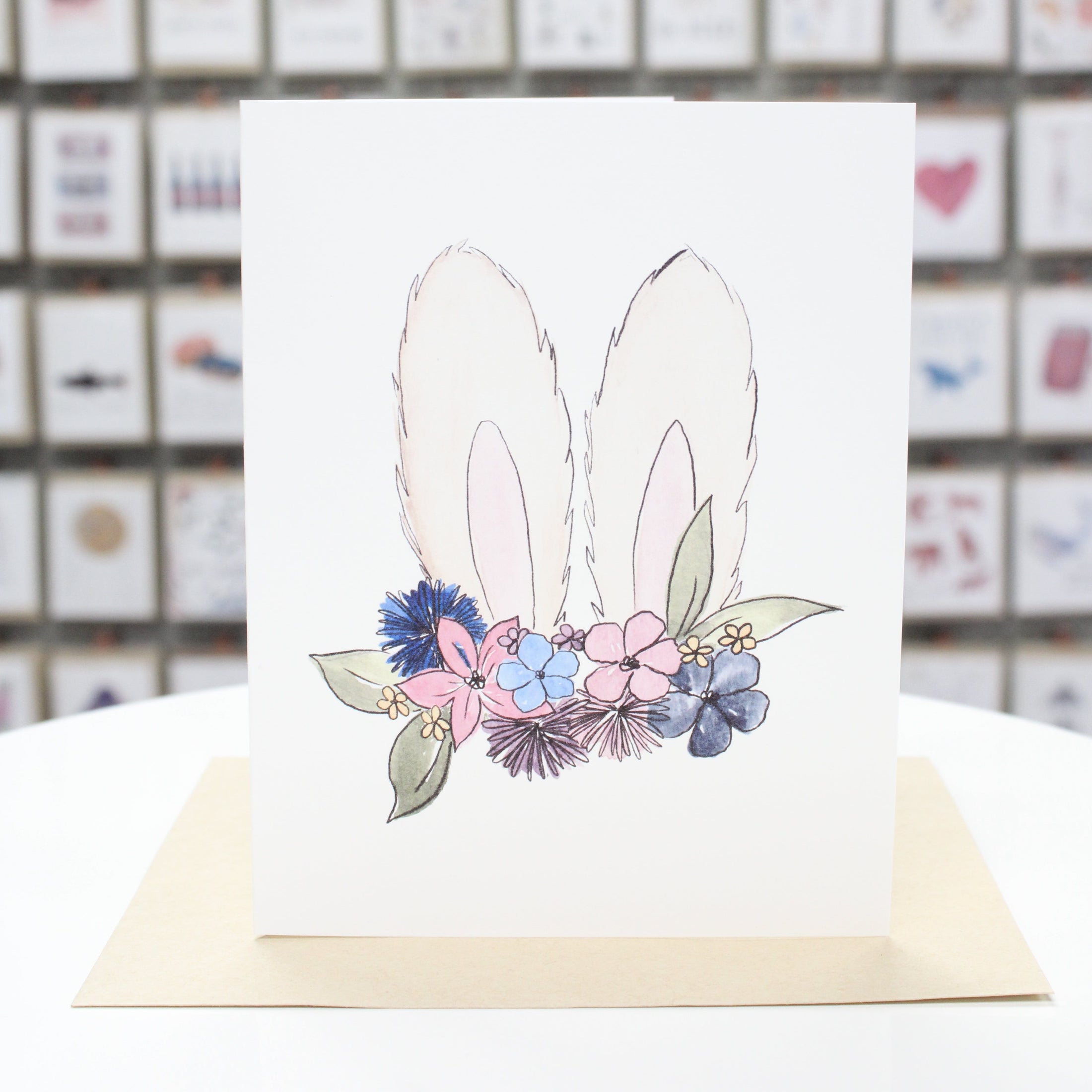 Hand crafted Easter greeting card with hand drawn fluffy bunny ears wearing colored flowers. 